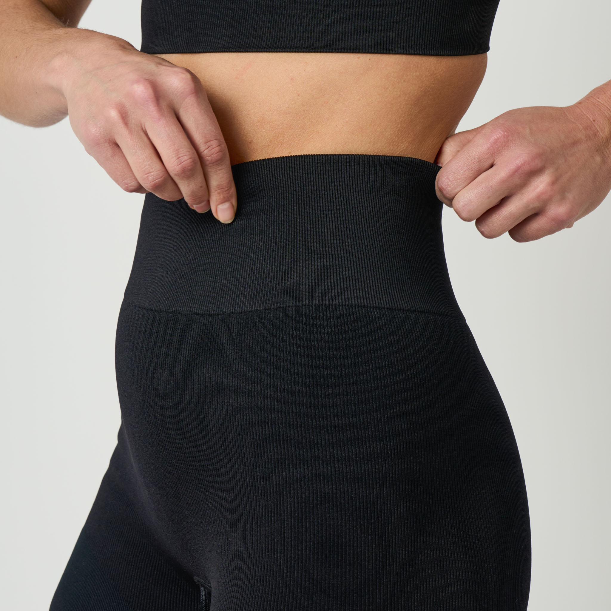 Person wearing black leggings with a plain background