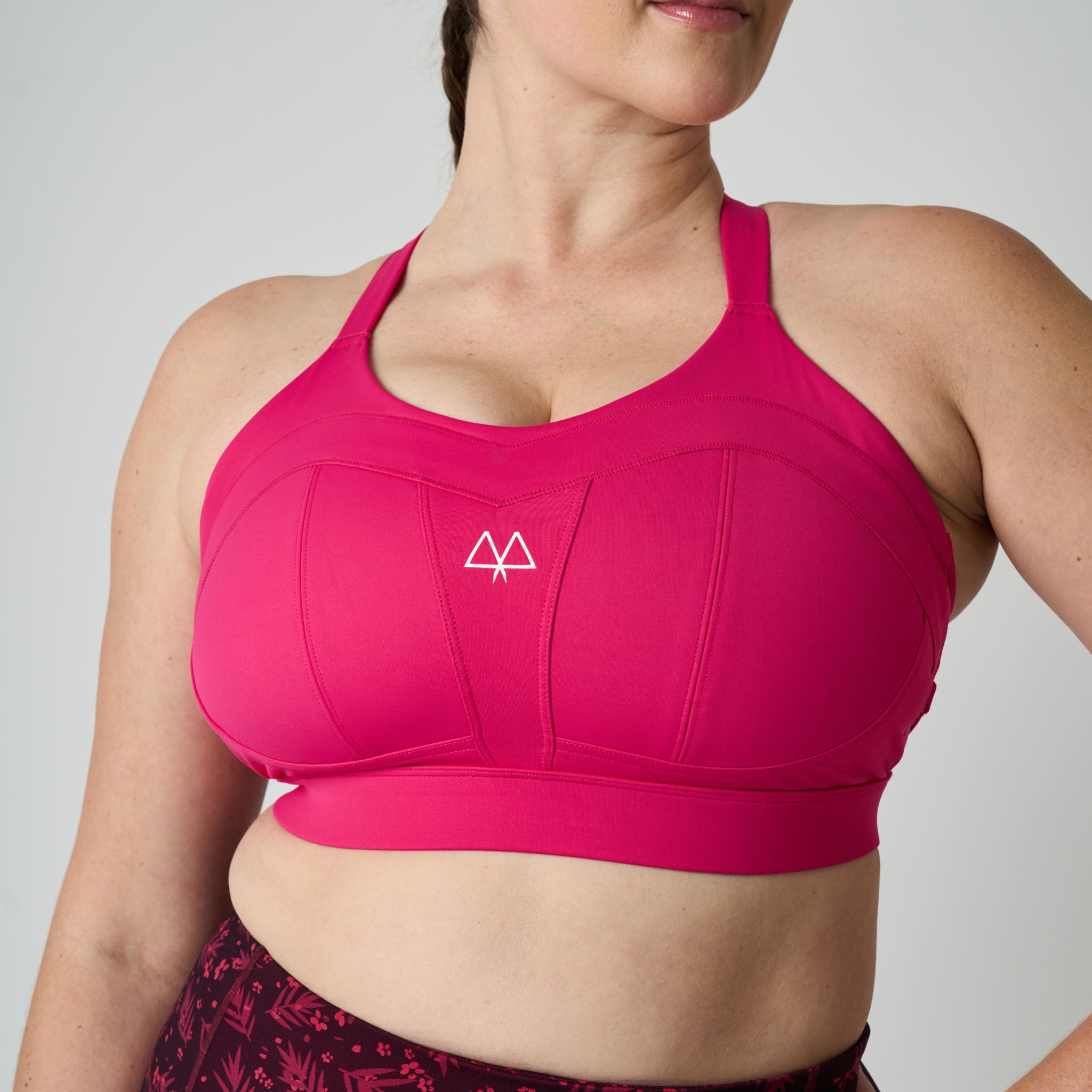 Pink sports bra with a logo on a plain background