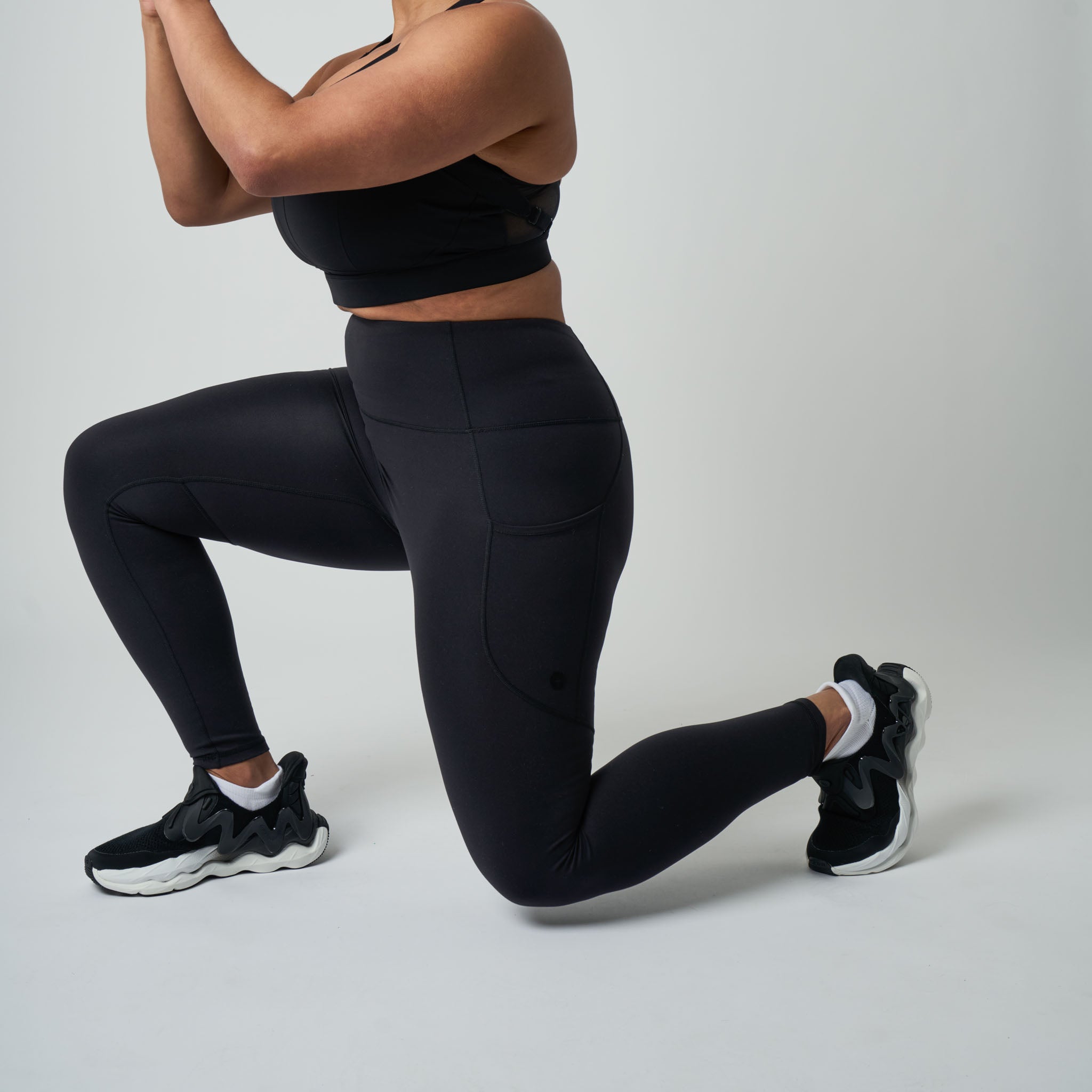 Person wearing black athletic leggings and top on a light gray background