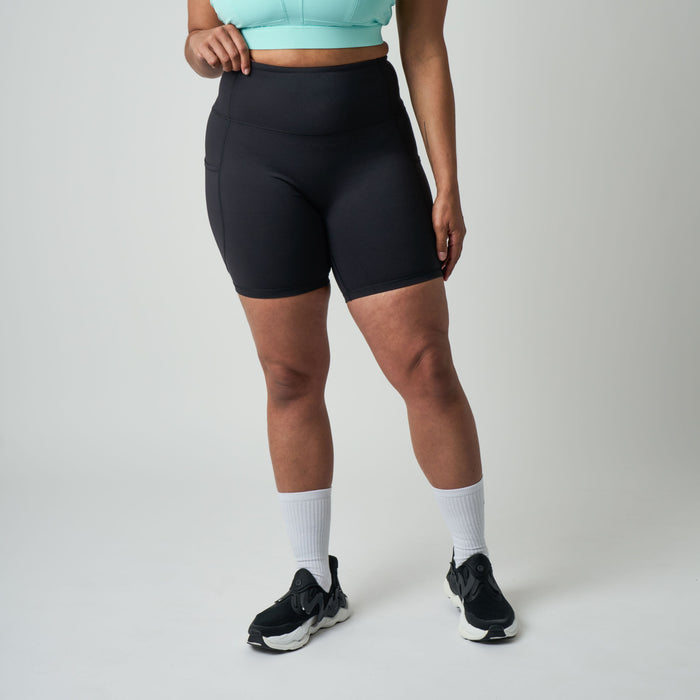 Person wearing black athletic shorts on a plain background