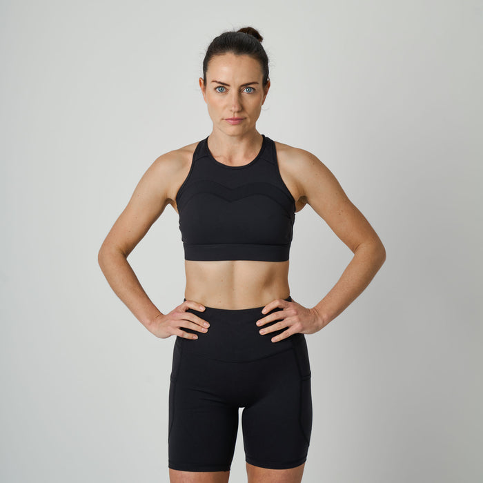 Woman wearing a black sports bra and shorts on a gray background
