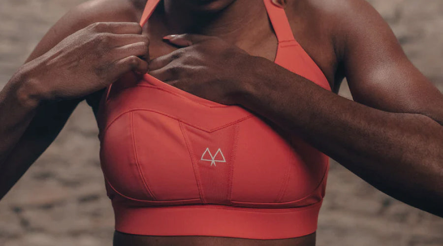 Girl wearing a coral coloured maaree sports bra and adjuting herself