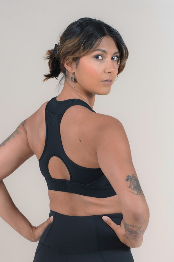 Athlete standing with her back facing with a Black Empower MAAREE Sports Bra on.