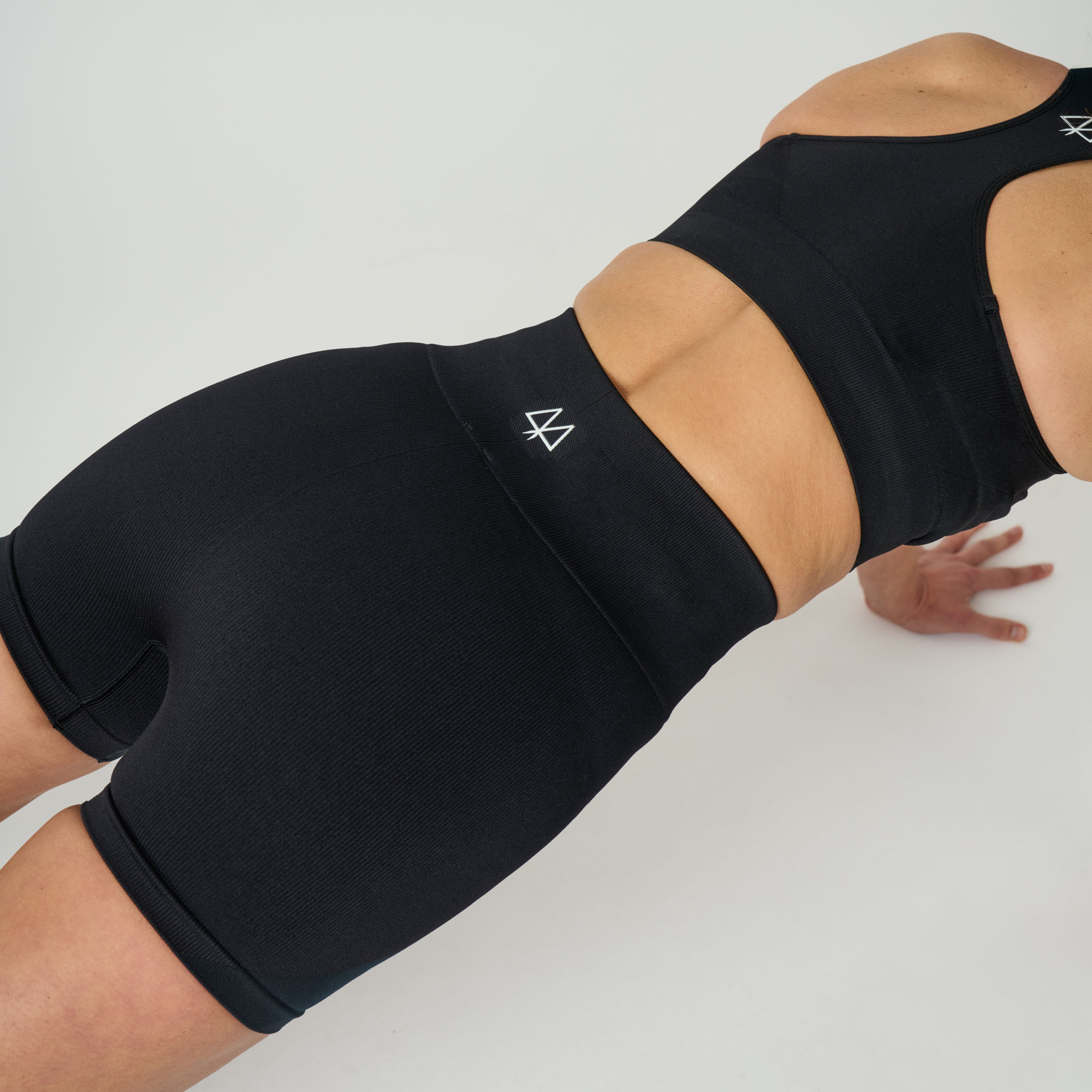 Person wearing black athletic shorts and top on a white background