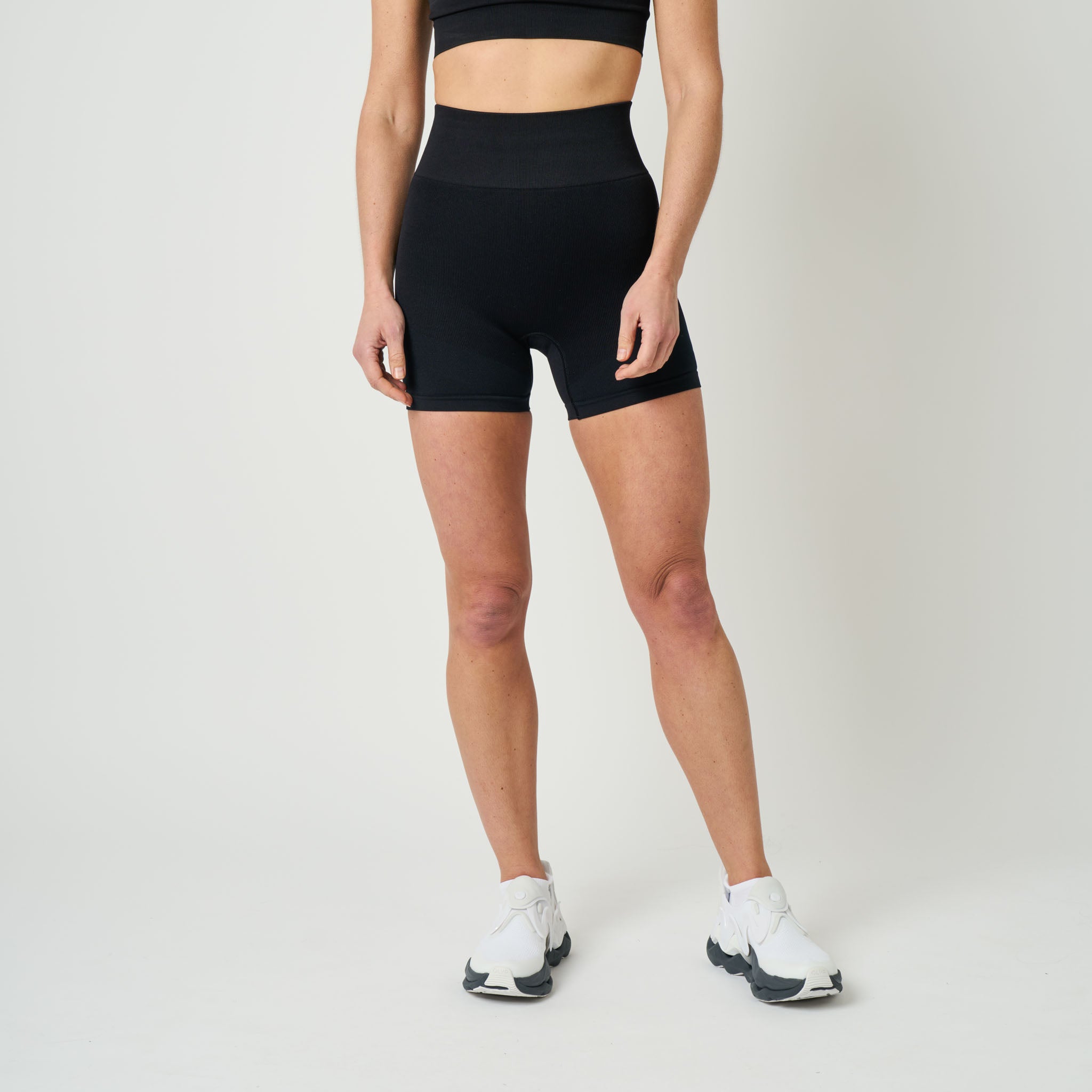 Person wearing black athletic shorts on a plain background
