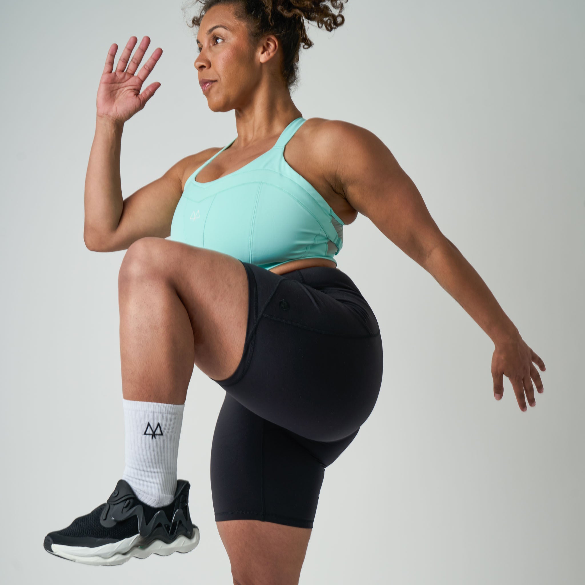 Woman in athletic wear performing a leg exercise on a plain background