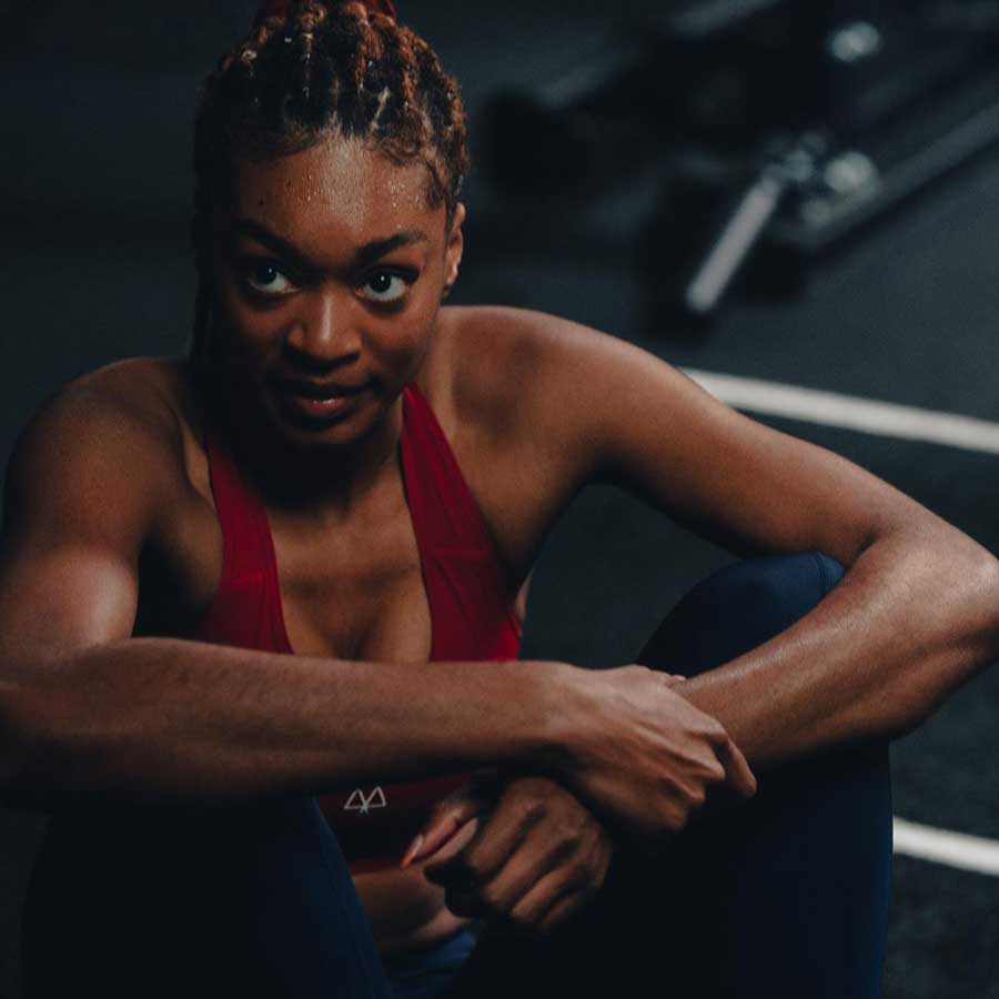 Athlete sitting in the gym after a hard workout, wearing the MAAREE medium support sports bra and leggings